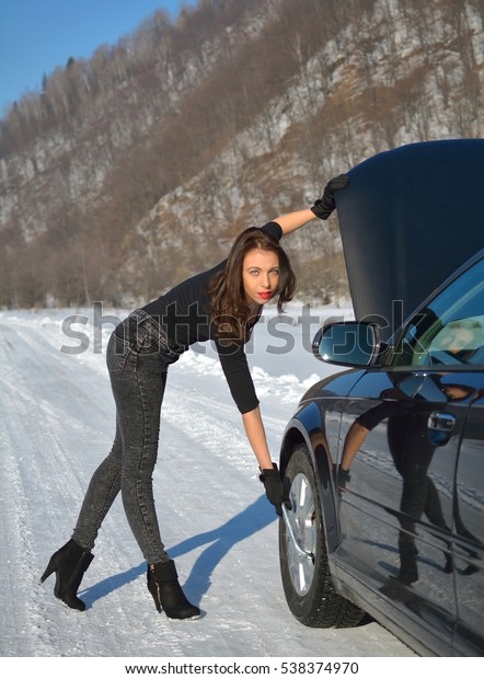 Winter car breakdown - young fashion woman trying to\
fix the car
