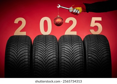 Winter car tires, big wheels service and hand of mechanic man with wrench and christmas ball on red background - Powered by Shutterstock