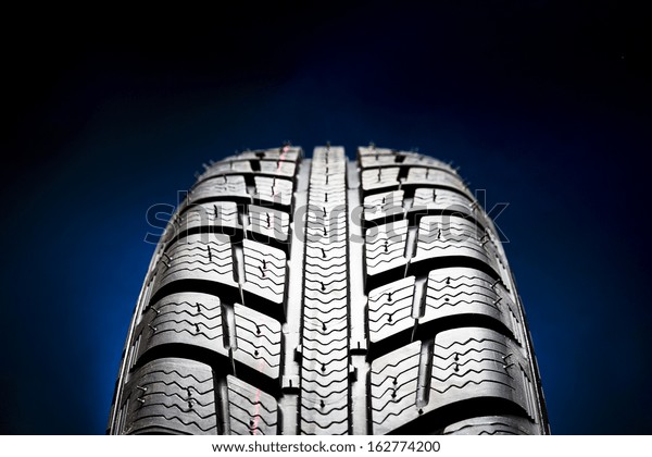Winter Car tires close-up wheel profile\
structure on black blue\
background