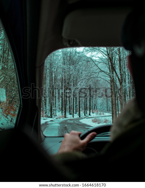 Winter car trip on a\
road absorbed in woods