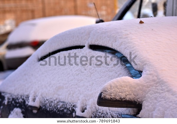 Winter cars in the yards are covered by a thick\
snow coat.