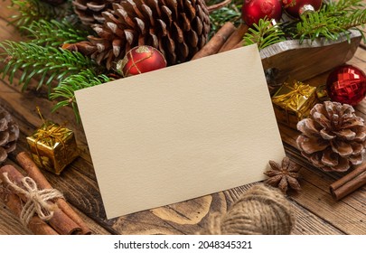 Winter Christmas Composition with a blank card on a wooden table close up Christmas and New Year greeting card template with fir tree branches, pine cones and Chritmas decorations. Holiday mockup