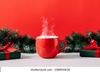 Winter or christmas cozy composition, steaming cup coffee or hot drink, Xmas decoration, branch fir, gift, on red background. Christmas, New Year, winter concept. Front view, copy space - Powered by Shutterstock