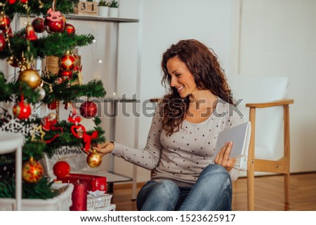 Winter, christmas, holidays and people concept. Pretty woman sitting on floor beside decorated christmas tree.