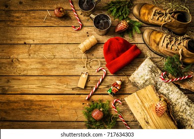 Winter Christmas Weekend In Country Cottage (cabin) Concept. Boots, Hat, Hot Drinks, Candy Canes And Firewood. Rustic Layout, From Above (flat Lay). Vintage Wooden Background With Free Text Space.