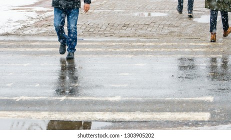 Winter City Slippery Sidewalk. Feet Of People Walking Along The Icy Snowy Pavement In Crosswalk In Snowfall. Pair Of Shoe On Icy Road In Winter. Abstract Empty Blank Winter Weather Background.