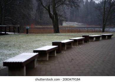 Winter cityscape. semicircular row of wooden benches covered with snow. snowy road in the park, copy space