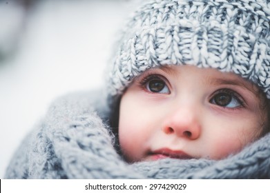 winter close up outdoor portrait of adorable dreamy baby girl in grey knitted hat and scarf - Powered by Shutterstock