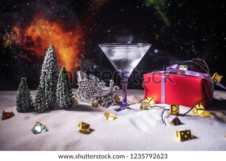Winter Cocktail - Alcoholic drink and snow scene with a Christmas theme or Ideas and recipes for Christmas drink. Glass of martini on snow with Christmas decoration, copy space