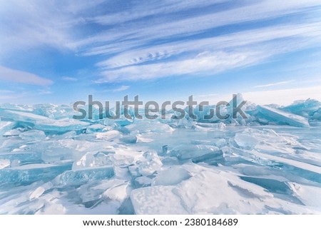 Winter cold seascape with pile of blue ice floes on frozen Baikal Lake against backdrop of blue sky with layered clouds. Natural background, Scenic unusual landscape