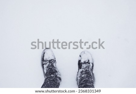 Winter coming concept. Top view of feet in a deep snowdrift. The time of year is winter.