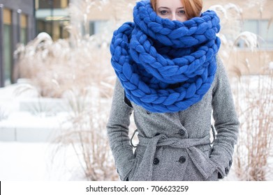 Winter is coming: redhead girl wearing a giant knitted scarf
