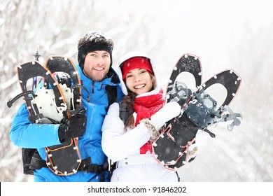 Winter Couple Happy Outdoor Hiking In Snow On Snowshoes. Healthy Lifestyle Photo Of Young Smiling Active Mixed Race Couple Snowshoeing Outdoors. Asian Woman, Caucasian Man.