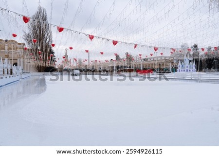 Winter day. Empty ice skating rink at an open-air amusement park. A specialized machine prepares the ice for skating