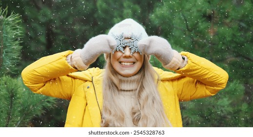 Winter day, happy smiling woman with snowflakes decoration toys having fun enjoys snow, warm weather against Christmas tree, joyful girl in yellow jacket, hat standing on snowy forest background - Powered by Shutterstock