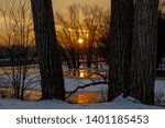 A winter day at sunset looking between two trees on the Wisconsin River at sunset.