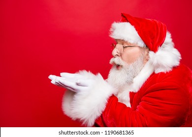Winter December sale discount black friday. Profile side view aged Santa in costume blow on open palms hand near face pouted lips isolated on shine red background with copy space for text - Powered by Shutterstock