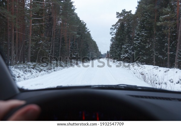 Winter Driving. Driving car through forest by small\
snowy road.