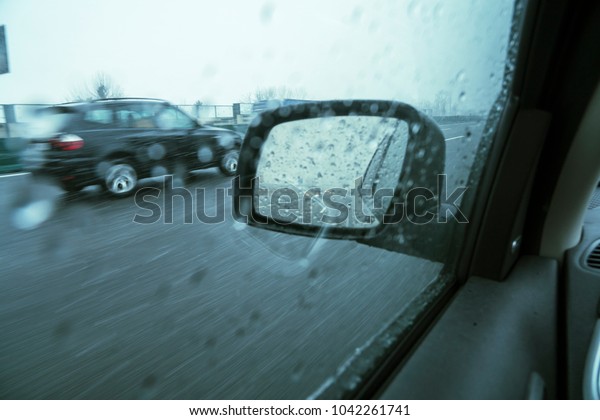 Winter\
driving, rear car mirror during a snowfall.\
