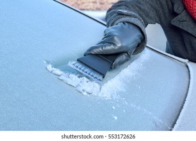Winter Driving - Woman is scraping Ice from the frozen windows of her car