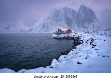 Winter early morning in Norway with red house, mountains and rocky coast.