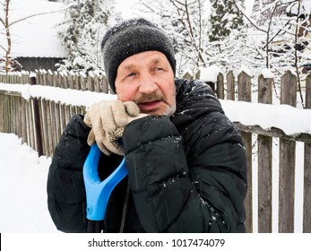 Winter. An Elderly Man Leans On A Snow Shovel