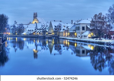 Winter evening in the snow covered old german town near Munich on the river Isar