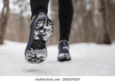 Winter exercise fitness lifestyle athlete walking with running shoes on snow and slippery ice needing traction soles on icy sidewalks. Run outside in cold weather.