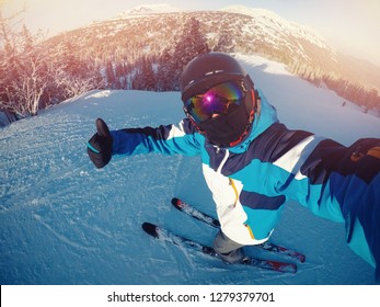 Winter Extreme Sport With Selfie Action Camera. Man Rides On Slopes Skis In Protective Helmet.