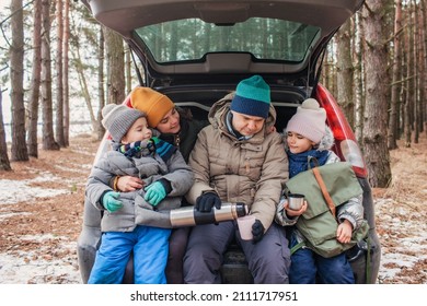 Winter Family Road Trip. Happy Parents With Kids Drink Coffee In The Trunk Of Car During Walking In Snowy Pine Forest, Travel Together In Any Season, Active Lifestyle, Authentic People