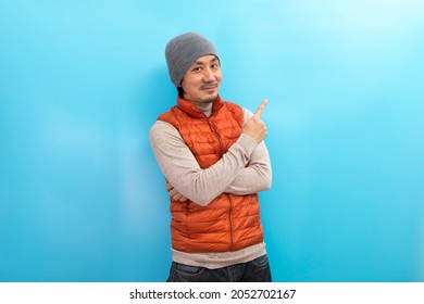 Winter Fashion. Handsome Asian  Man In Hat And Scarf Pointing Finger Over White Isolated Background.