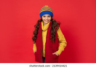 Winter Fashion. Happy Kid With Curly Hair In Hat. Female Fashion Model. Teen Girl In Down Vest.