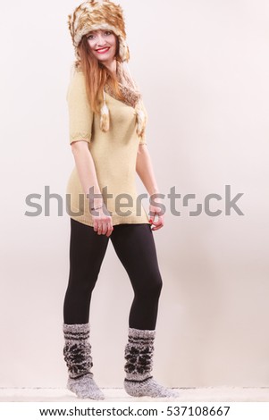 Winter fashion. Happy young woman in full length wearing fashionable wintertime clothes fur cap woolen warm socks posing