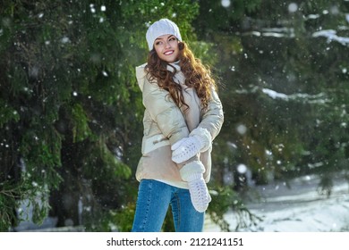 Winter fashion. Portrait of a beautiful girl in fashionable winter clothes, who is standing in a winter park on a sunny day and smiling. Winter activities.