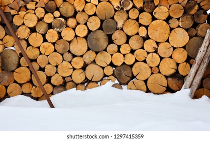 Winter Firewood Stock Near The Snow Mound. Rustic Background.