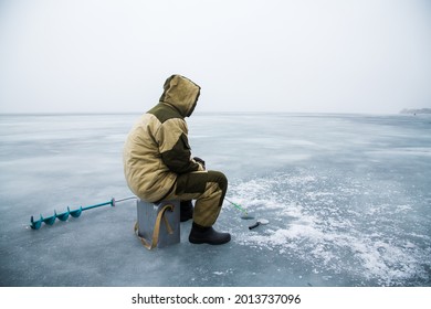 Winter Fishing On A Frozen Lake. A Fisherman Catches Fish On The Ice Of A Frozen Lake