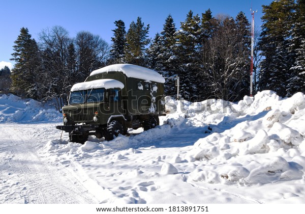 In a\
winter forest, in a clearing full of snow, there is a truck covered\
with snow. Winter, a lot of snow covered the forest, a truck with\
chains on wheels and in the snow\
stands.