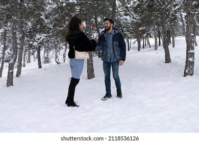 In the winter forest in love walks . winter holidays. A couple hugs and laughs on a background of a snowy forest.  young couple guy and a girl in a snowy forest. Giving valentines day red rose. 