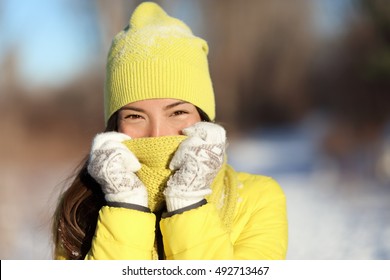 Winter Freezing Woman Covering Face From Cold. Skincare Concept. Cute Asian Girl Happy Holding Scarf With Gloves Over Nose And Mouth To Protect From The Frost. Warm Outerwear For Wintertime Season.