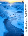 Winter frosty landscape.  Landscape with  river and snowy forest in Western Siberia. Freezing river against sunset background. Frosty winter evening.