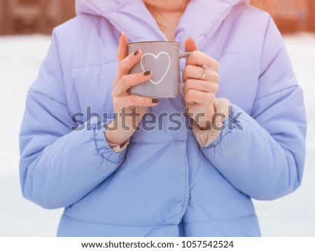 Winter frosty morning. The girl's hands hold a beautiful hot cup with a drink. Part of the body. Drink, fashion, morning. Heart.