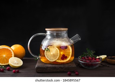 Winter fruit tea. Citrus and berry tea with cranberries, lemon, oranges  in glass teapot on dark wooden table, copy space. Fruit tea. Seasonal winter autumn hot drink. - Powered by Shutterstock