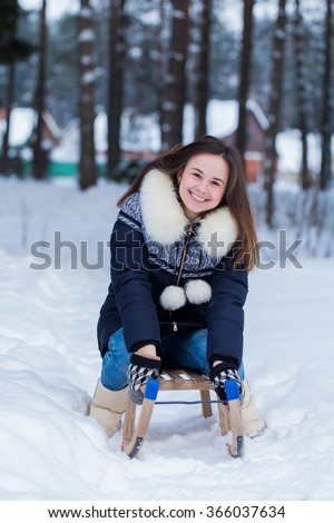 Winter fun of young woman on sleds.