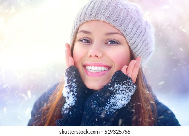 Winter Girl Portrait. Beauty Joyful Teenage Model Girl Touching Her Face Skin And Laughing, Having Fun In Winter Park. Beautiful Young Woman Laughing Outdoors. Enjoying Nature.