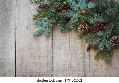 Winter greenery, pinecones and berries against rustic wood backdrop.