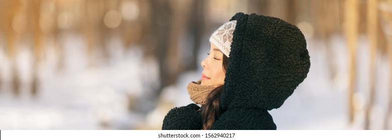 Winter Happy Woman Relaxing Breathing Cold Air Outside Young People Lifestyle. Asian Girl With Closed Eyes Breathing Wellness And Health In Forest Wearing Hooded Jacket And Hat Panoramic Banner.