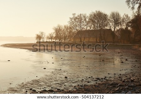Winter hazy landscape with lake starting to freeze