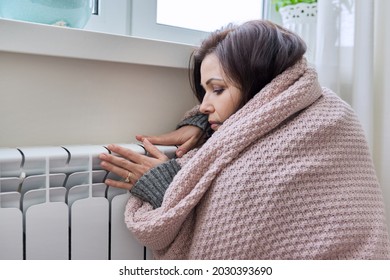 Winter, Heating Season. Woman In Warm Sweater Sitting In Home Room Near Heating Radiator