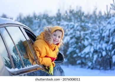 Winter Holiday. Boy Child Is Leaning Out Of The Car Window And Enjoying Snow Road And Forest Winter. Happy Kid Travel With Family On The Car.