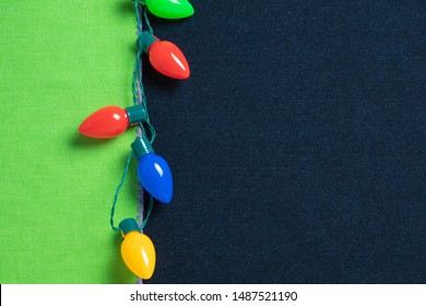 Winter Holiday Or Christmas Background With Bright Green And Dark Denim Background And A String Of Old Fashioned Tree Lights In Red Blue Yellow And Green